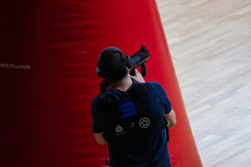 Боец LASERWAR вскинул оружие у красного барьера